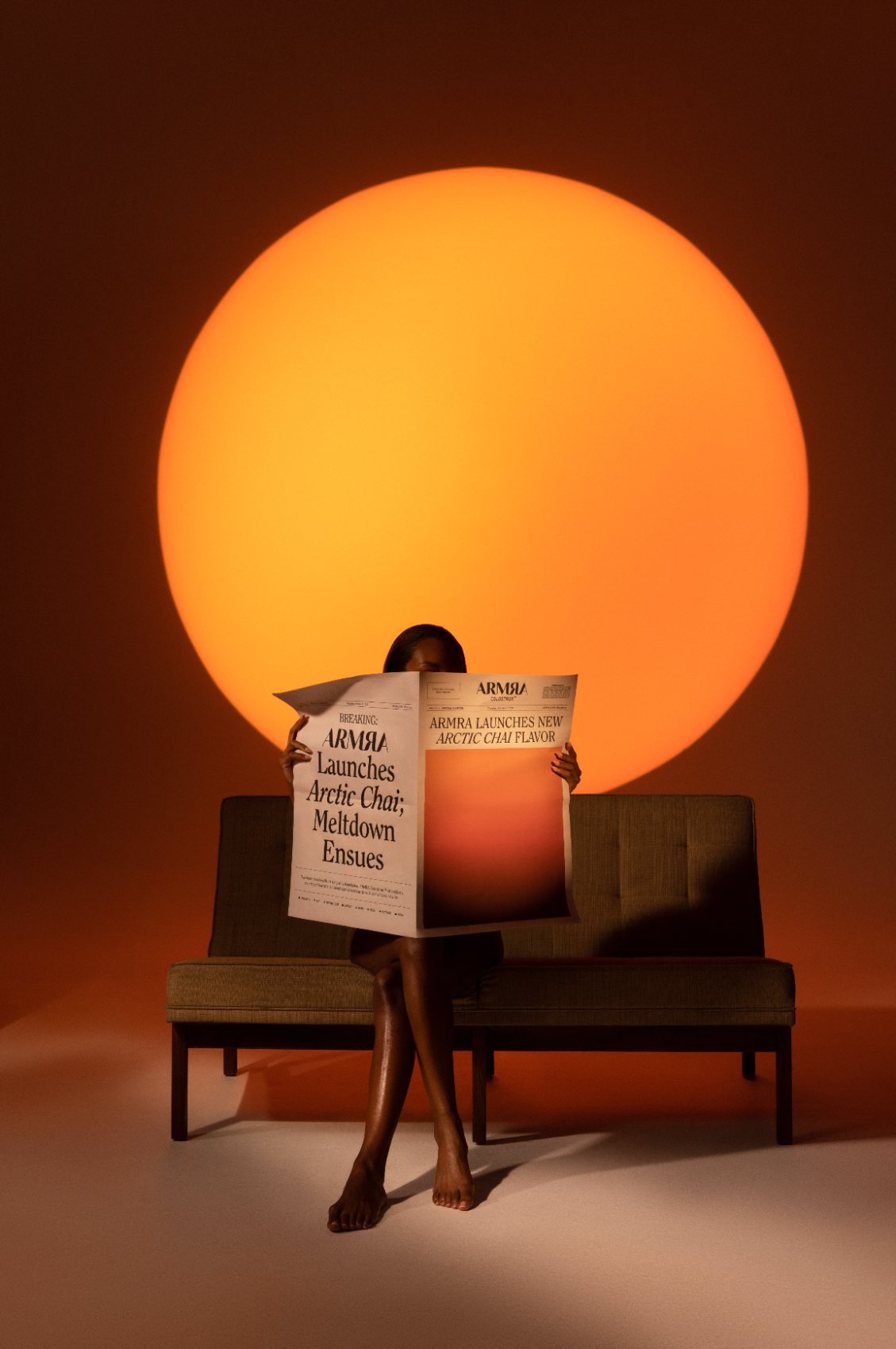 Person on a bench reading a newspaper under a large orange sun