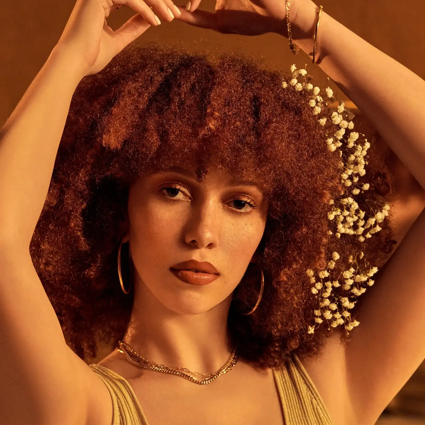 Model with curly hair and baby’s breath, arms raised