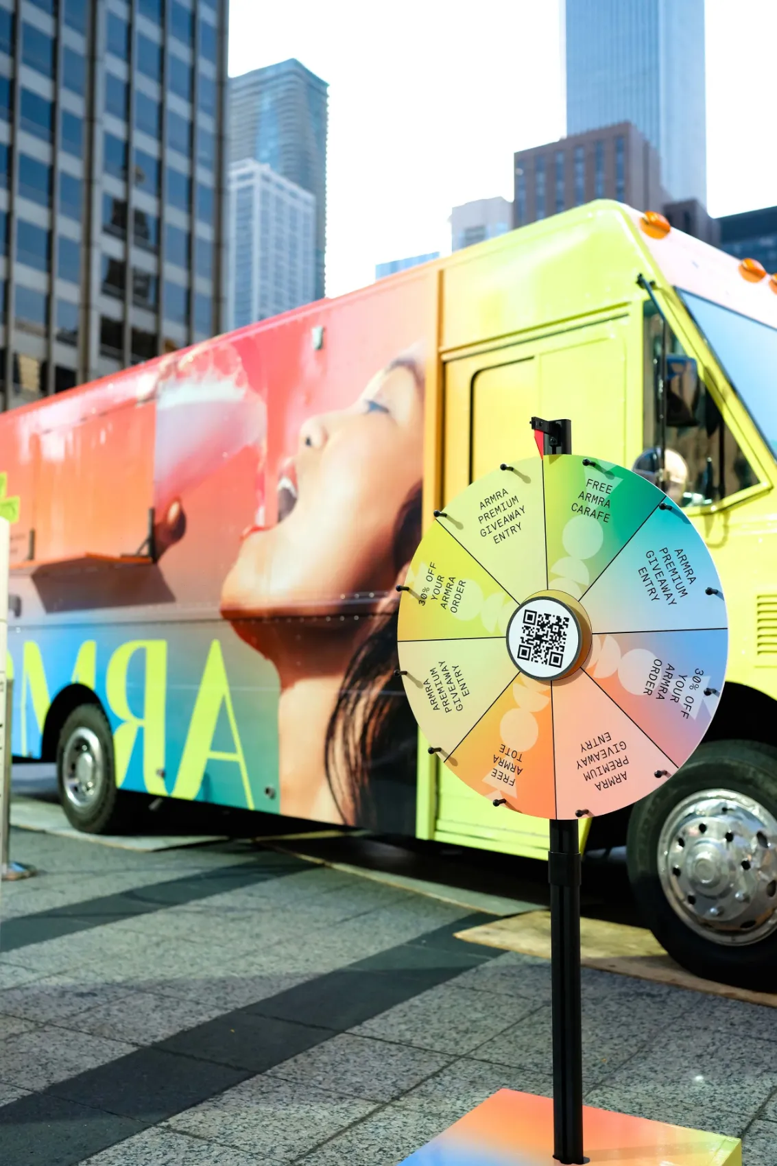 Colorful ARMRA truck with a prize wheel on a downtown plaza