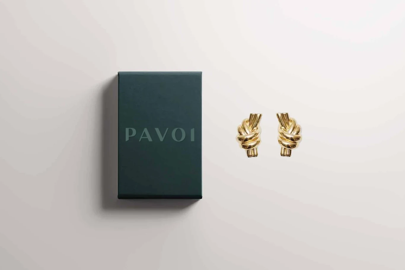 Forest-green PAVOI jewelry box with a debossed wordmark beside gold earrings